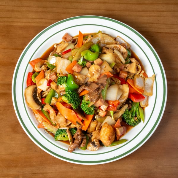 A colorful stir-fry with broccoli, carrots, mushrooms, and meat in a rich sauce on a white plate.