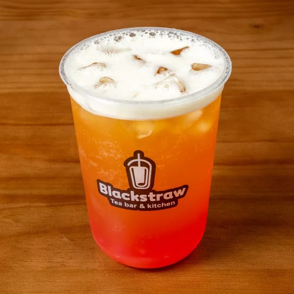 Blackstraw Tea Bar & Kitchen's iced tea with a creamy foam topping on a wooden table.