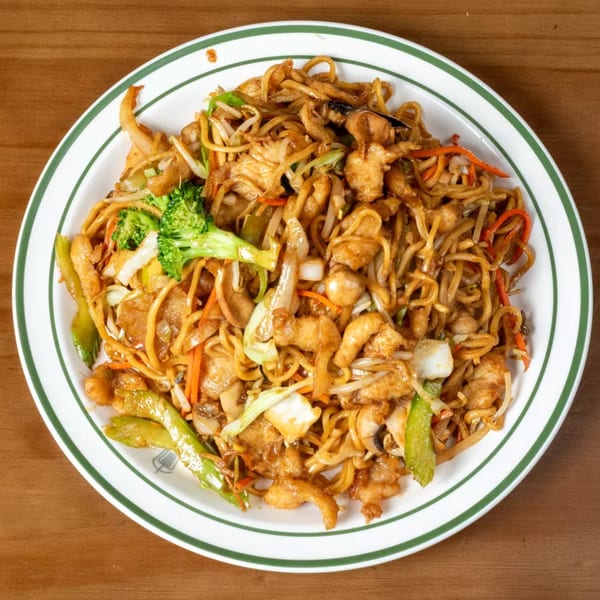 A white plate with green stripes holds a large serving of chicken lo mein with vegetables.